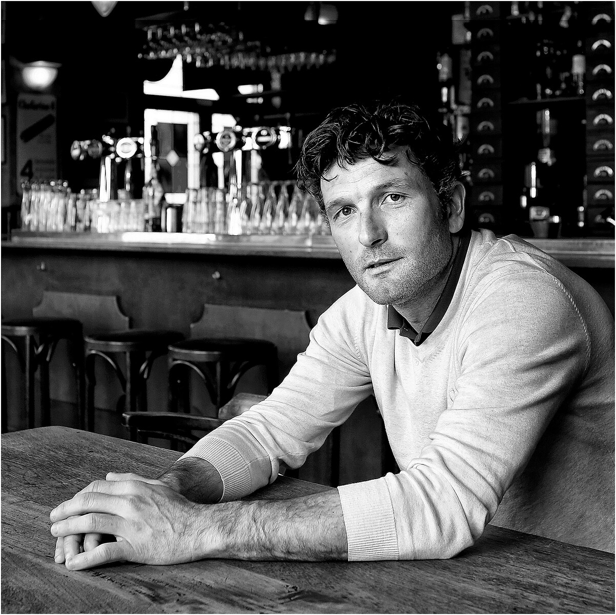Zwart-witportret van een man aan een cafétafel